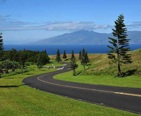 Winding road in Kapalua, Hawaii with the coast and mountains in the background