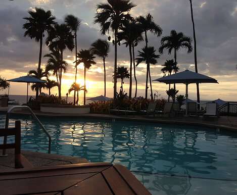 Maui, Hawaii resort hotel swimming pool and palm trees at sundown